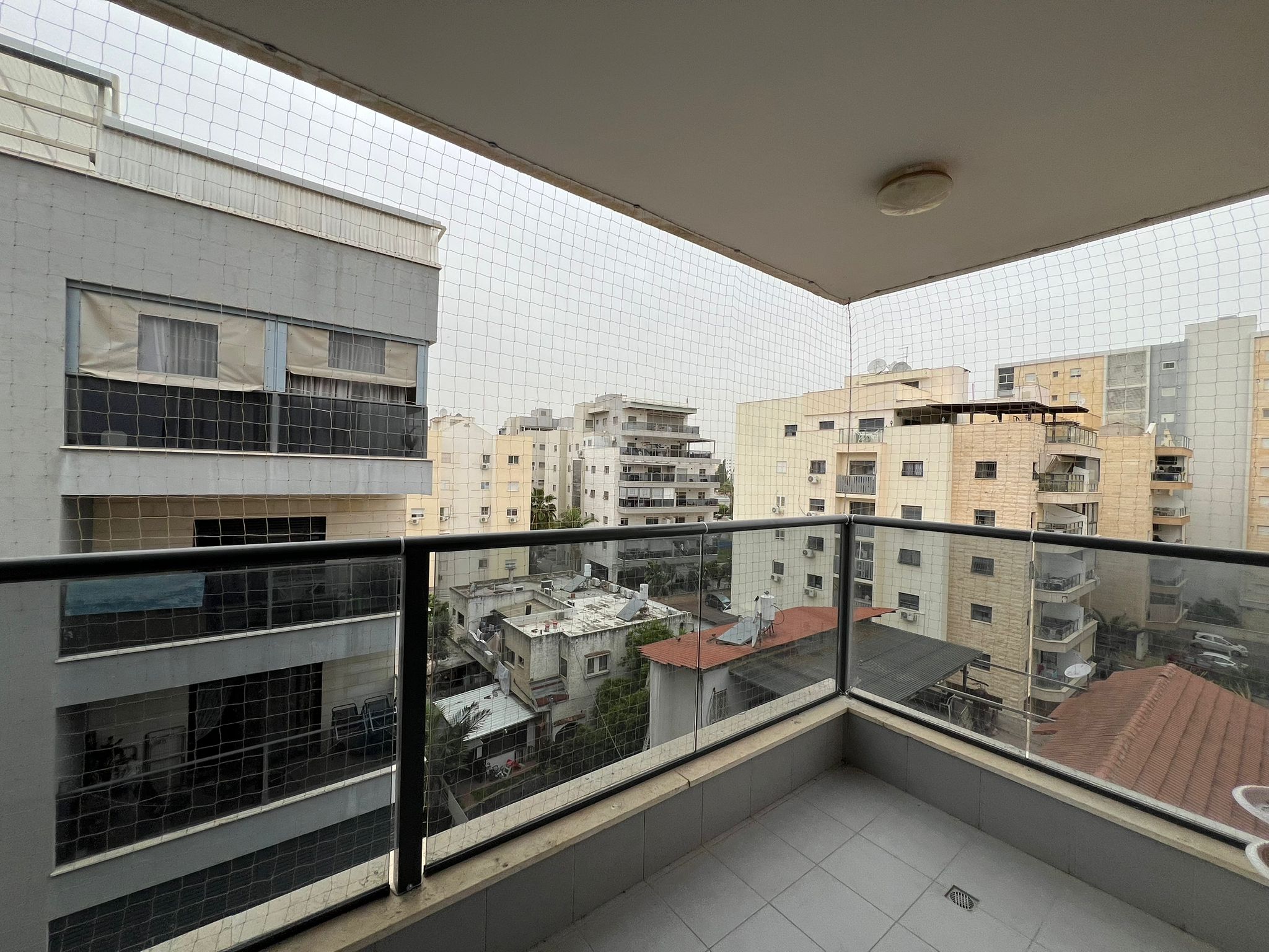 מרפסת דירה נקייה עם מעקה זכוכית לאחר הרחקת יונים